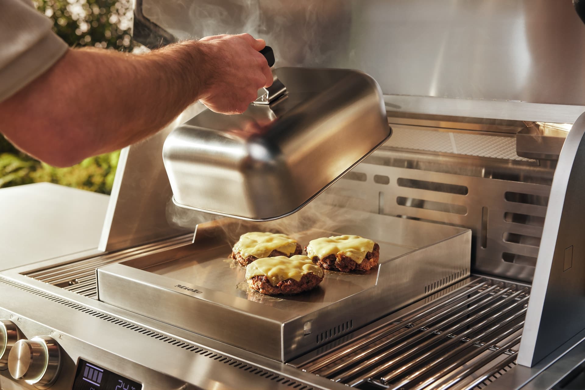 Miele Fire Pro Gasgrill mit Burgern unter der Grillhaube